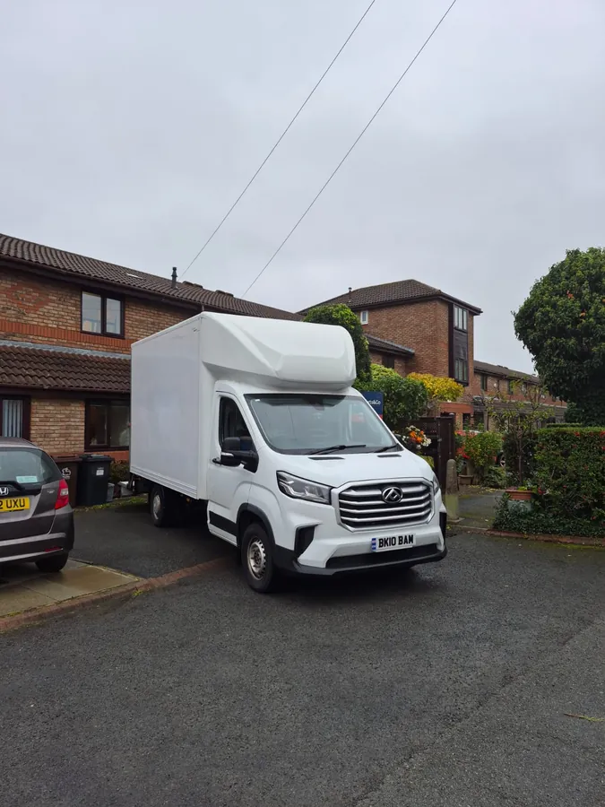 The Luton van pulled onto a driveway outside a brick house on an overcast day