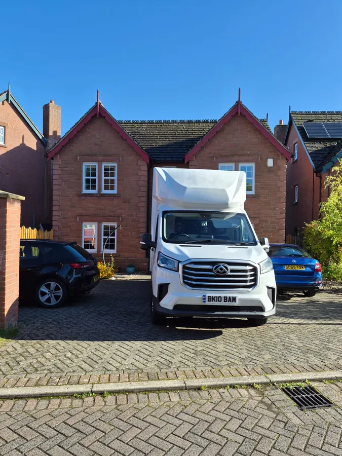 The Luton van on a block-paved drive outside a red sandstone house in sunshine