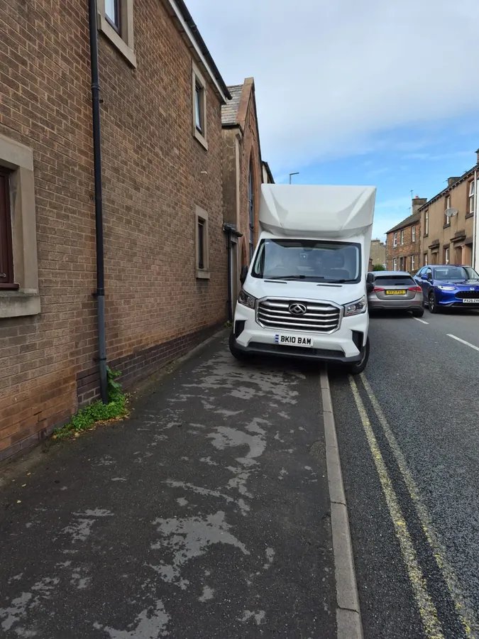 The Luton van parked up on a terraced street beside an old brick building